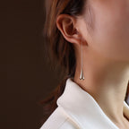 long teardrop earrings flat lay gold rose gold titanium
