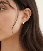 gold teardrop stud earrings worn on model ear close up