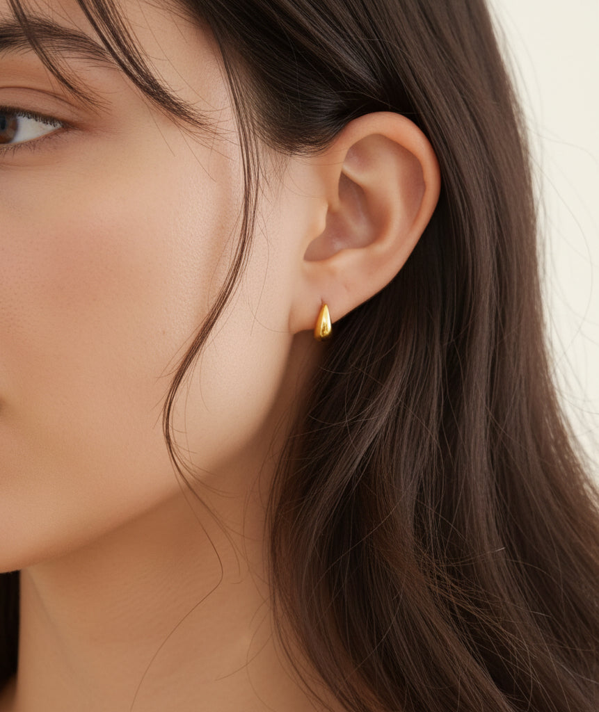 gold teardrop stud earrings worn on model ear close up