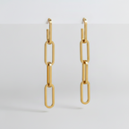 Gold paperclip-style earrings on a light gray background